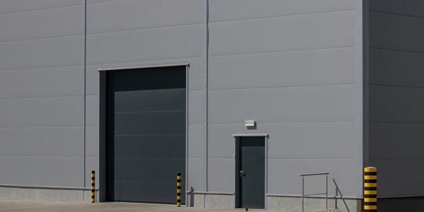 Industrial building with a large closed garage door and a small door beside it.