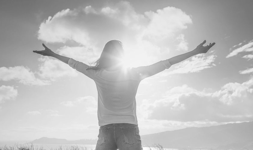 Thoughtful person looking toward an open horizon in warm natural light, peaceful, and hopeful