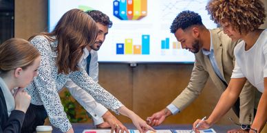 A diverse team collaborates over data charts in a meeting room.