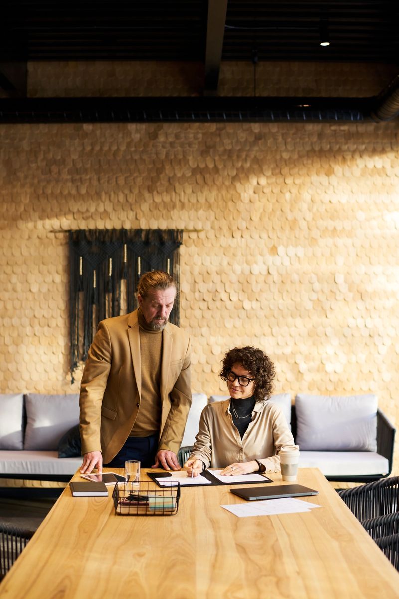 Two mature colleagues discussing financial documents or reading terms and conditions of contract while businesswoman pointing at paper