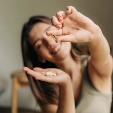 Woman holding a capsule, smiling.