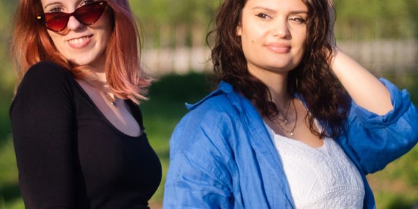 Two women enjoying a sunny day outdoors, one wearing sunglasses.