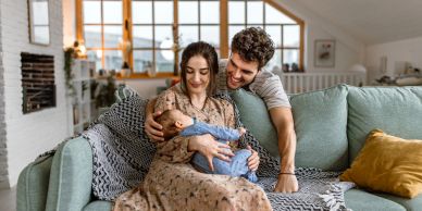 Happy couple holding their newborn baby on a couch.