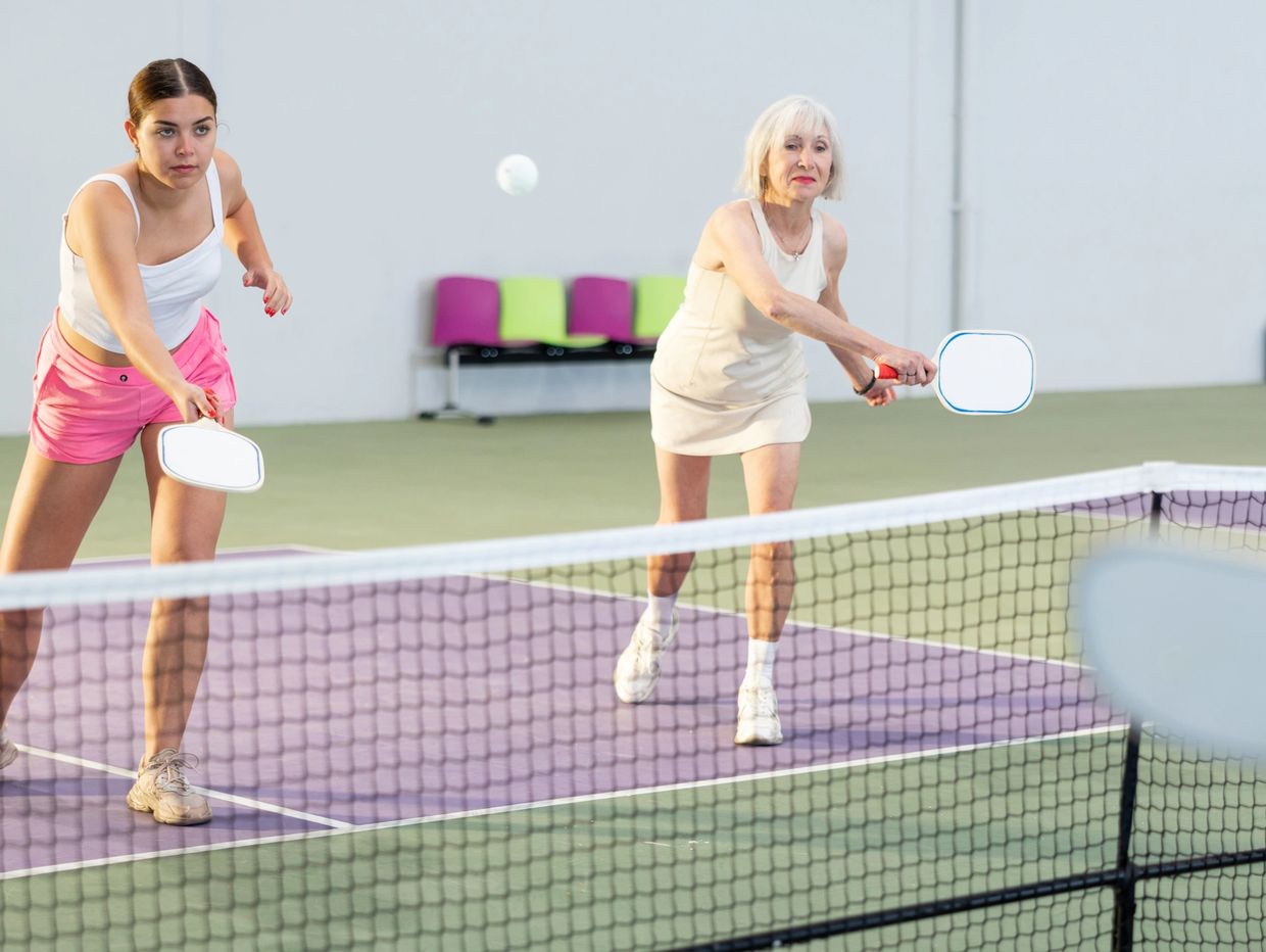 Two players hitting a pickleball on an outdoor court.

