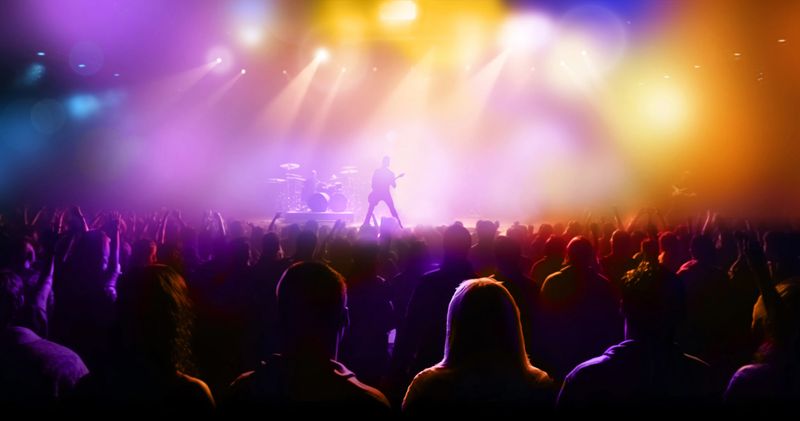 Silhouettes of concert crowd in front of bright colorful stage lights