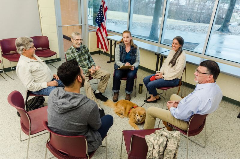 The multigenerational group of veterans sit in a circle for their recovery meeting at the army post.