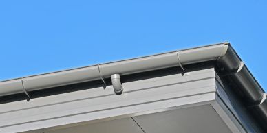 Close-up of a building roof edge under clear blue sky.