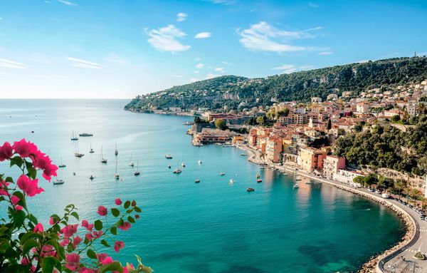 Scenic coastal town with boats and vibrant flowers.