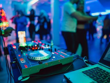 DJ controller and laptop at a vibrant dance party.