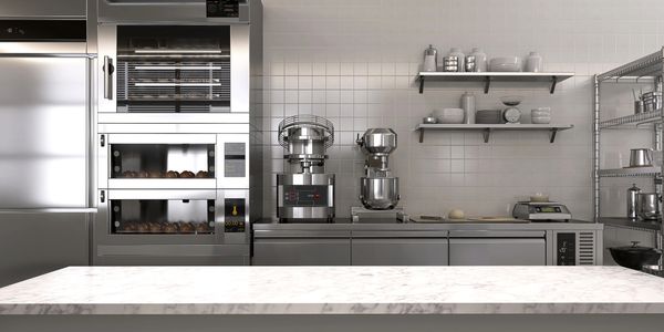 Modern bakery kitchen with stainless steel appliances and marble countertop.