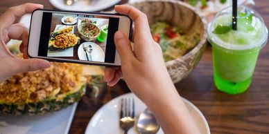 Person photographing a meal featuring pineapple fried rice and a green drink.