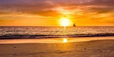 Sailboat sailing on the ocean during a vibrant sunset.