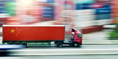 A red cargo truck with China's flag speeding on a highway.