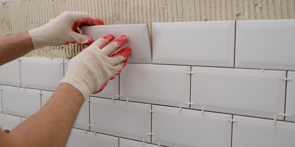 Professional installing gray floor tiles during home improvement process.

