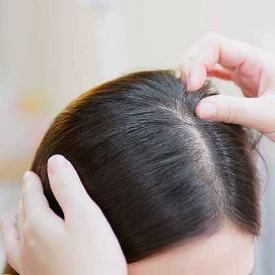 Person examining scalp and hair closely.