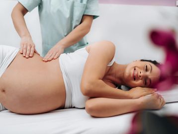 Pregnant woman receiving a massage, smiling.