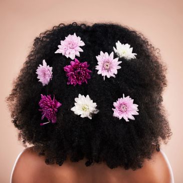 Curly hair adorned with colorful flowers.