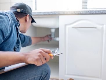 Lavabo altındaki boruları inceleyen tamirci.