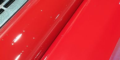 Close-up of a shiny red car surface with reflections.