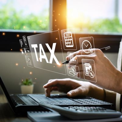 Person using laptop and stylus with digital tax icons floating around.