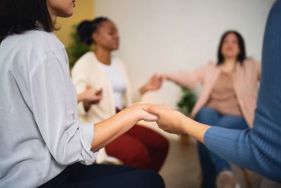 Group of women sitting in a circle holding hands.  