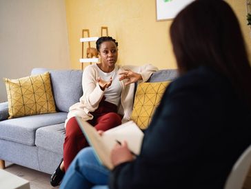 Generic image of a consulting room. Lady of sofa talking, another sat  taking notes and listening. 