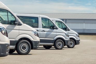 Photo of a row of white fleet vehicles parked outside next to each other.