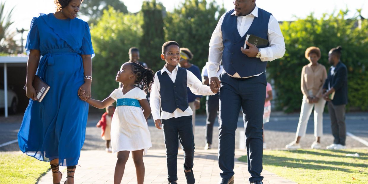 A family dressed elegantly walking hand in hand outdoors.