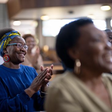 People clapping and smiling in an indoor setting.