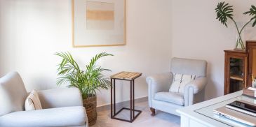 Cozy, minimalist living room with light armchairs and plants.