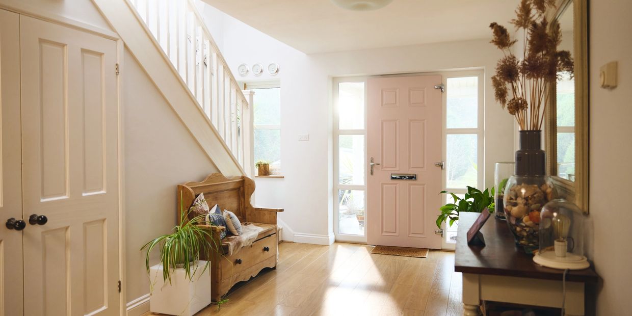 Cozy and bright entrance hallway with wooden bench and pastel pink door.