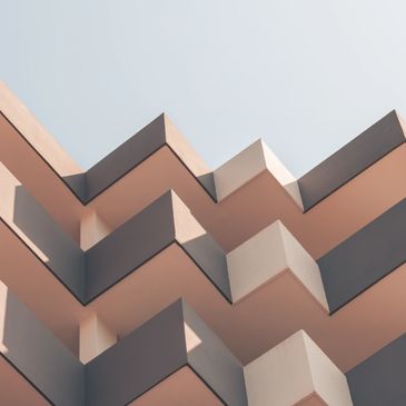 Modern building balconies with geometric zigzag patterns under clear sky.