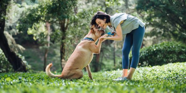Woman affectionately interacting with her dog outdoors.