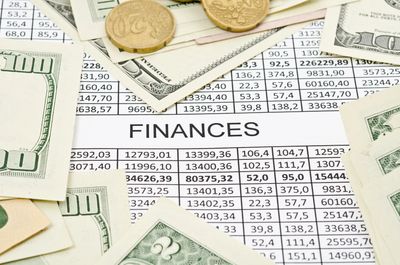 A spreadsheet displaying finances and dollars and coins scattered on top