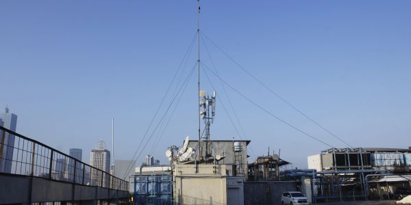 Rooftop with antennas and clear blue sky.