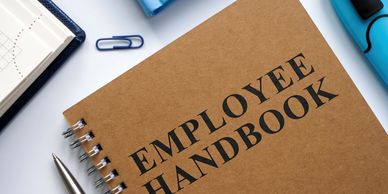 Employee handbook on a desk with office supplies.