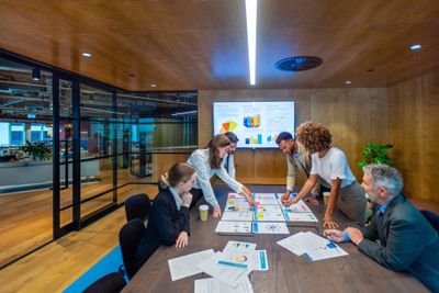 Team collaborating on project with charts and graphs in modern office.