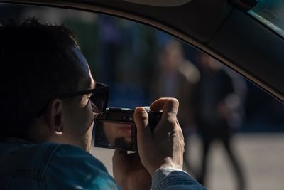 Man taking a photo from inside a car with a digital camera.