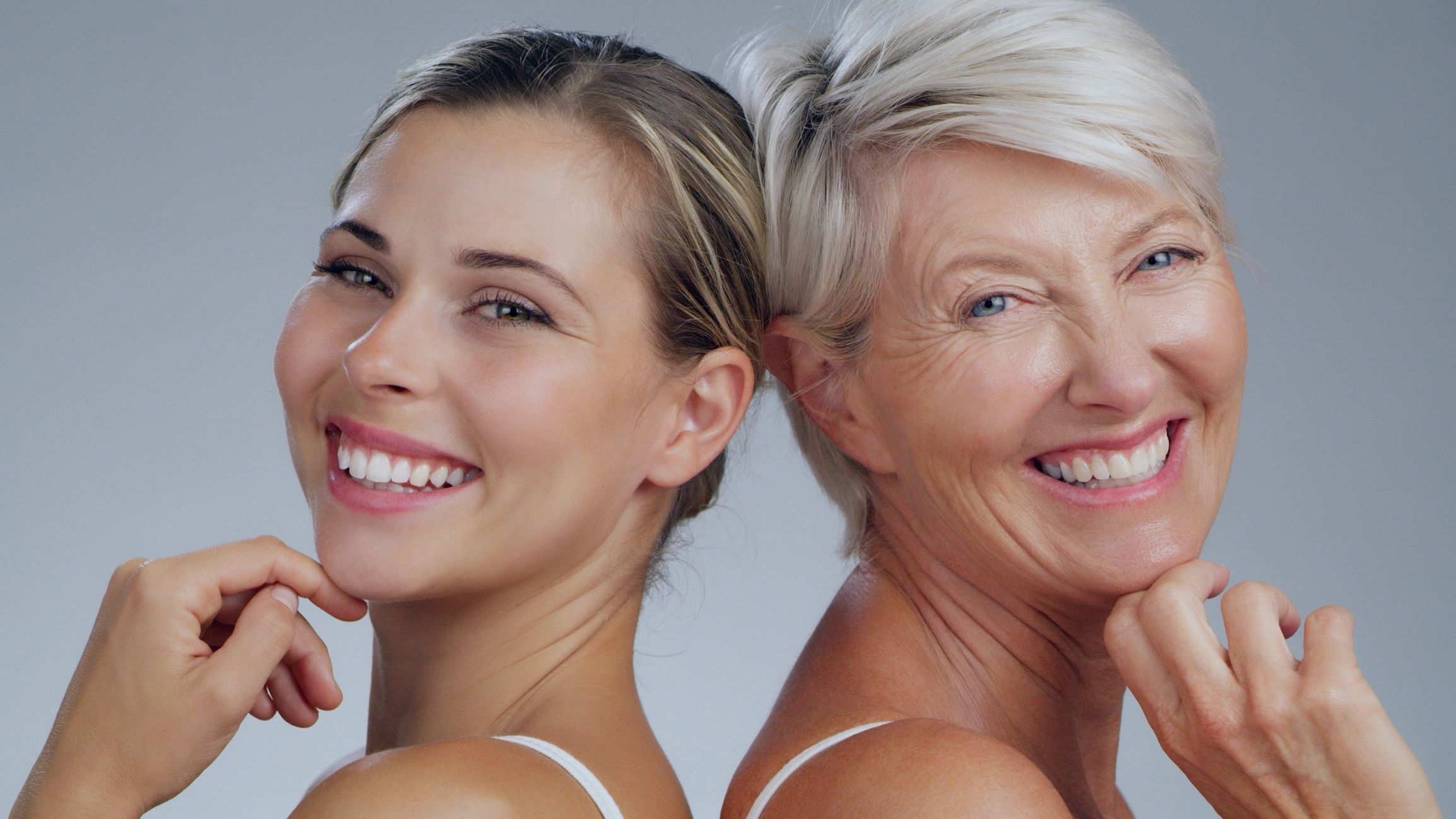 Smiling young and older women back to back showing youthful and mature healthy skin.