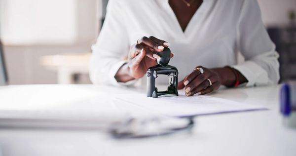 Person stamping documents at a desk.