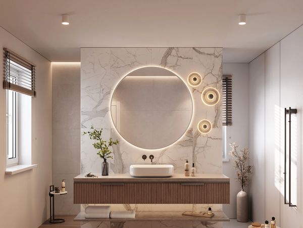 Modernes Badezimmer mit rundem Spiegel und indirekter Beleuchtung.