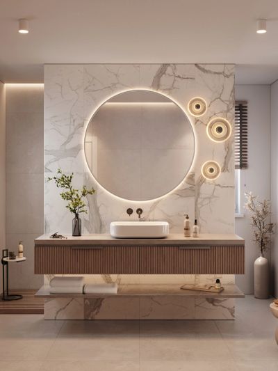 Modern bathroom with a round illuminated mirror and marble accents.