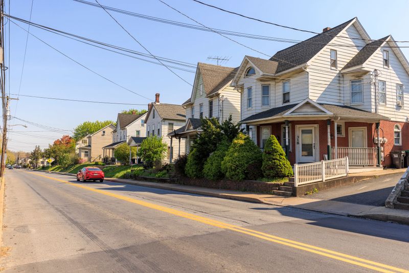 Two-lane street in luxury neighborhood: red car drive through Stockertown's Main street in Pennsylvania, Northampton County, Lehigh Valley, Poconos USA