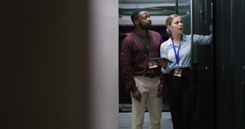Team, man and woman technician check server room for cloud computing or cyber security at night. Tech, it engineer and people working on database for maintenance or networking in data center