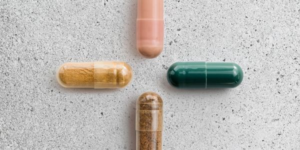 Four different colored capsules arranged in a cross on a textured surface.