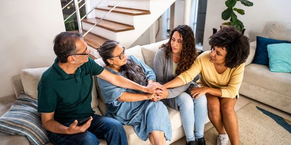 Four people sitting on a couch sharing a comforting moment together.
