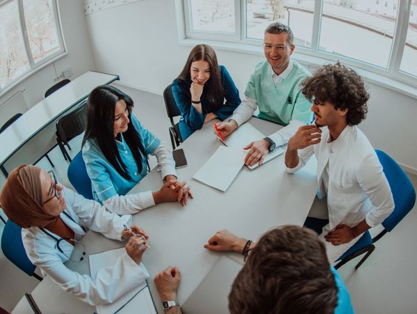 Medical team having a discussion around a table in a bright room.
