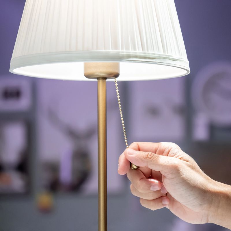 Buying lighting equipment concept. Male hand pulling light switch chain on white lamp in home decor store.