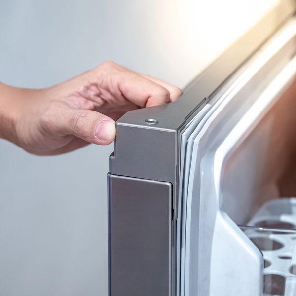 Hand opening a modern refrigerator door with a close-up view.