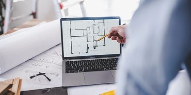 Person pointing at a floor plan on a laptop screen.